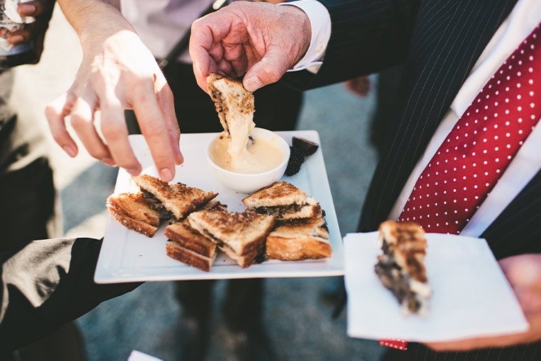 People dipping sandwiches in cheese | Lisa Dupar Catering | Wedding & Event Catering in Seattle